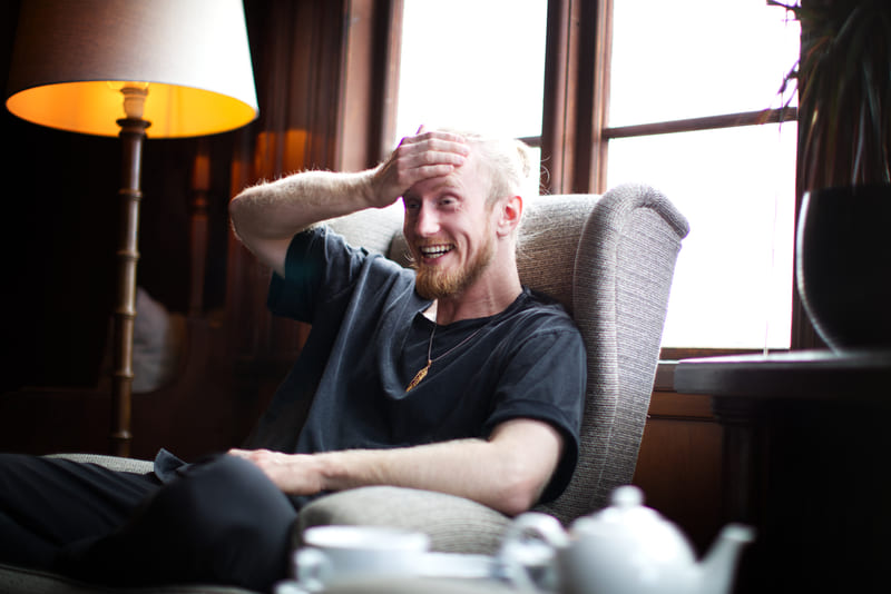 Fredrik Brännlund, founder of Noa The Game Fredrik Brännlund laughing with a hand to his forehead in an armchair by a window